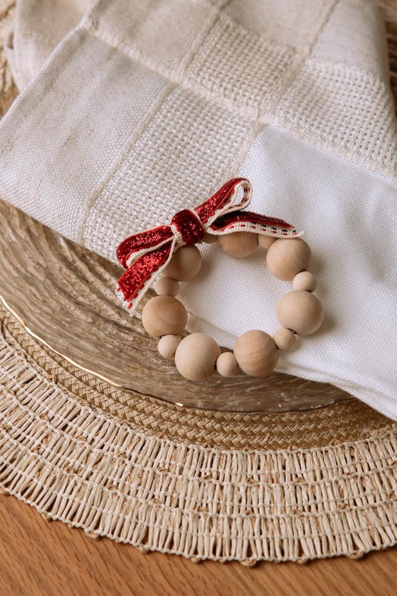 حلقة منديل خشبية ريفية مزينة بخرز وزينة عيد الميلاد من Words Co. - طراز ريفي مع فيونكة حمراء احتفالية