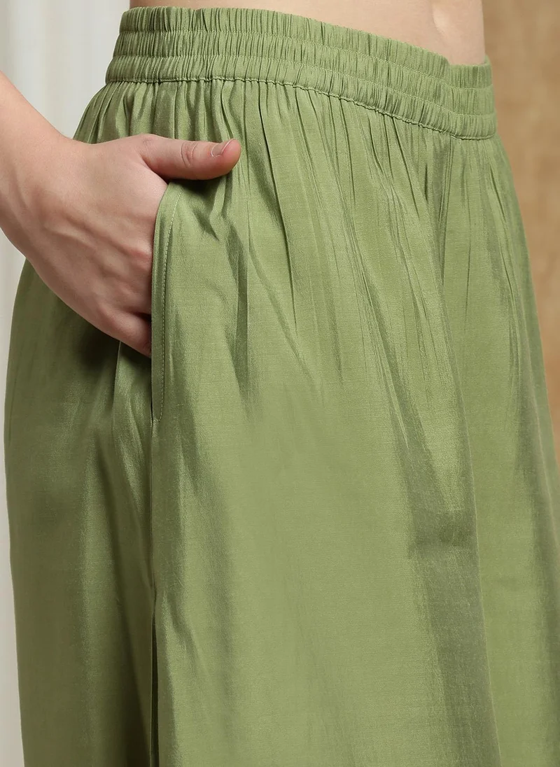 جلو باص طقم جلابيه نسائية باللون الأخضر بياقة مربعة وأكمام بشريط وتفاصيل ترتر وحافة دانتيل مع بنطلون بالازو ودوباتا بكشكشة للمناسبات