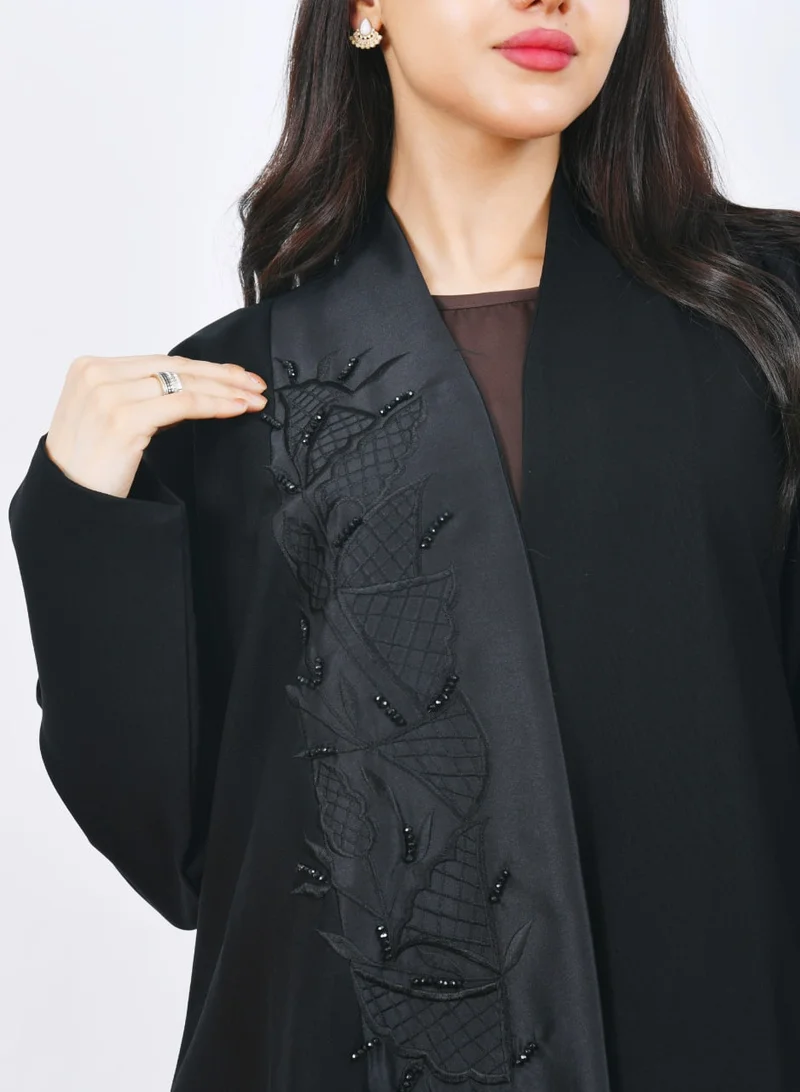 عبايات حوراء عباية سوداء أنيقة بتصميم فاخر بقَصّة نص كلوش مع تطريز بارز على الواجهة يضفي لمسة راقية وعصرية