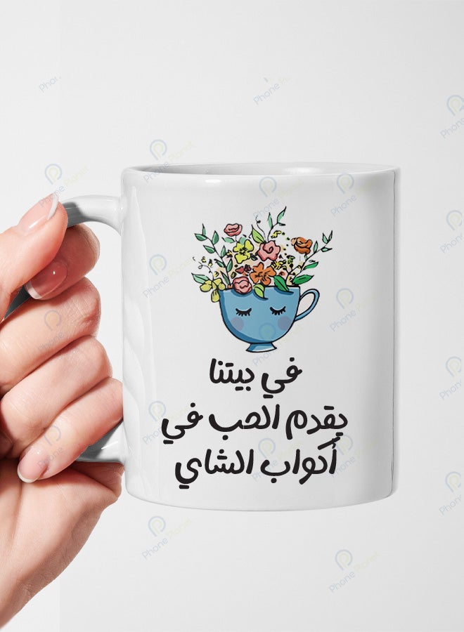 كوب من السيراميك مطبوع عليه عبارة في بيتنا يقدم الحب في أكواب الشاي ويتميز بمقبض مريح