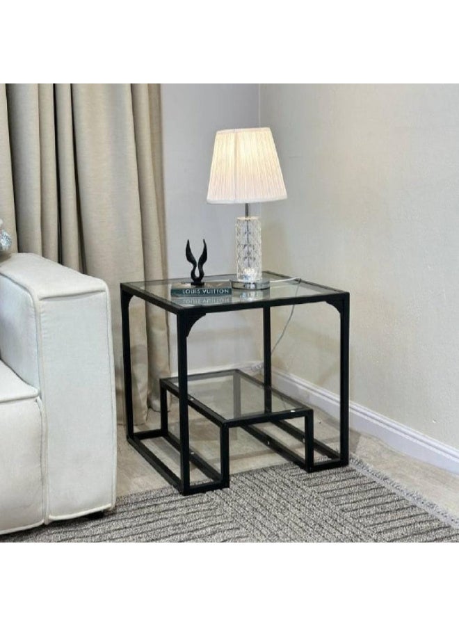 Modern side table with a transparent glass top and black iron legs.