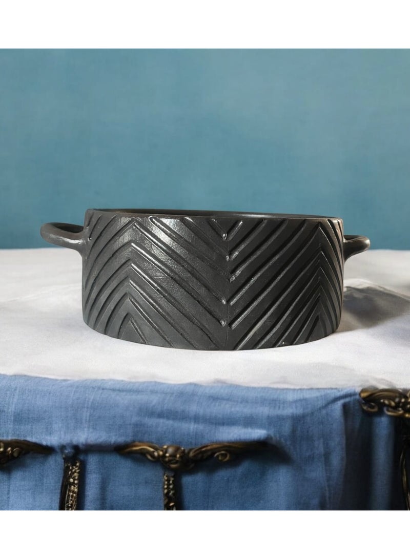 A 27cm black earthenware casserole dish that can withstand direct and indirect heat, suitable for use on a flame or in the oven. - Image 3