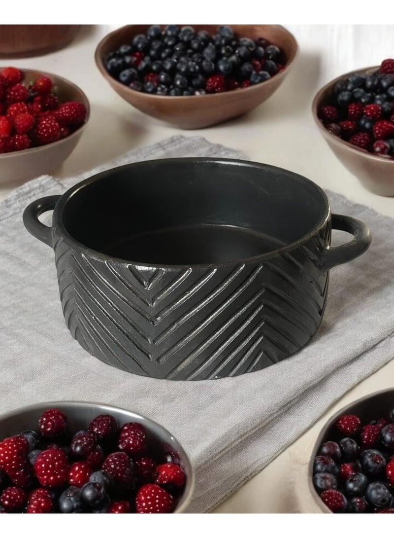A 27cm black earthenware casserole dish that can withstand direct and indirect heat, suitable for use on a flame or in the oven. - Image 1