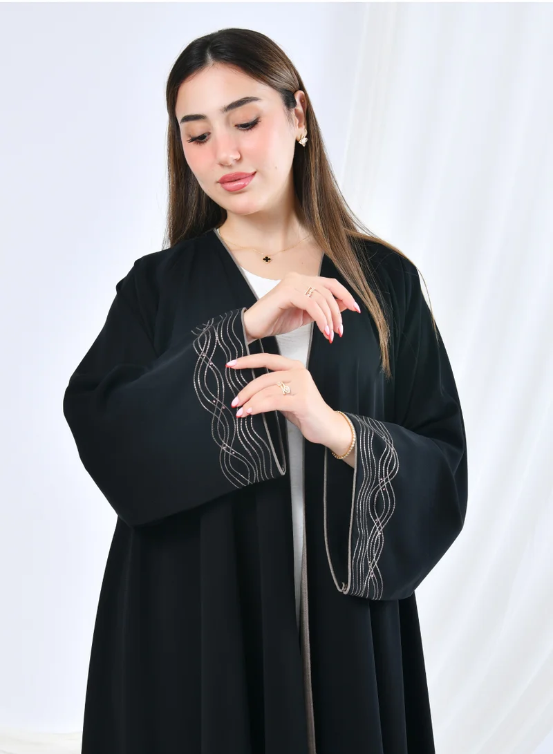 HAWRAA ABAYA Elegant flared abaya with a simple luxurious design and gold-embroidered sleeves adorned with beads.