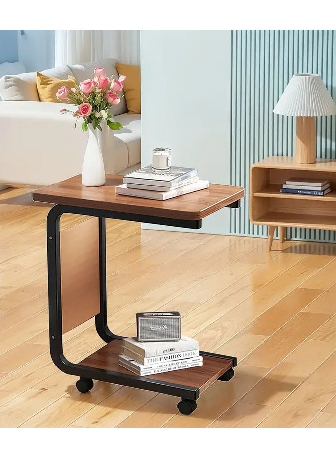 Generic Movable side table with C-shaped wheels, Gemini brown wooden top and durable black metal frame. Multi-functional. Includes a lower shelf for extra storage space and a side pocket for storing bill envelopes, notebooks, magazines or charging cable. Elegant and simple design, space-saving and easy to move thanks to the wheels. Lightweight and fits most decors and blends easily with other furniture. Practical for using a laptop, placing a phone, a coffee cup or TV remote, eating a snack or reading a book. You can place it next to the bed, in the living room, in the office to place a coffee tray or in the kitchen. Can be used as a kitchen cart  - Image 1