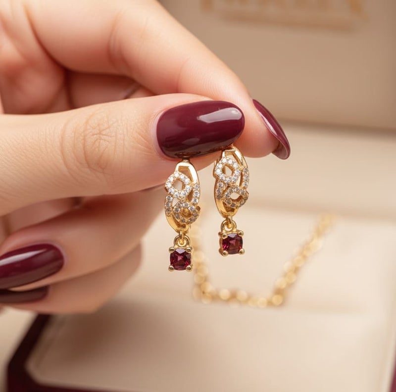 حلق رقيق مطلي باللون الذهبي بتصميم أنيق مرصع بفصوص براقة، يتدلى منه حجر كريم مربع بلون أحمر قرمزي ساحر. - Image 3