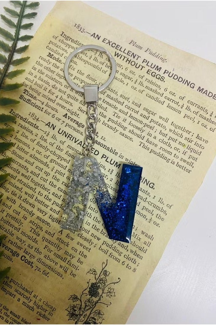 An elegant keychain with the letter N made of luxurious resin embroidered with silver leaf