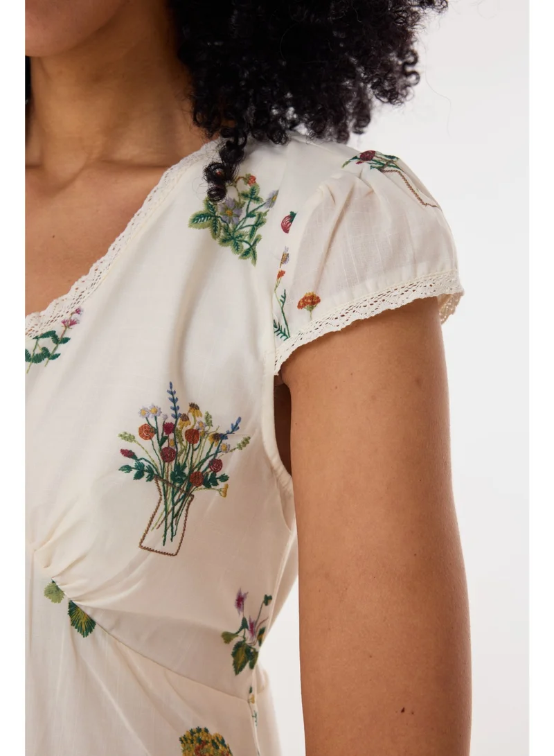 أشيتا فرنانديز فستان ميدي بطبعة زهور وياقة على شكل حرف  وأكمام كاب – عاجي