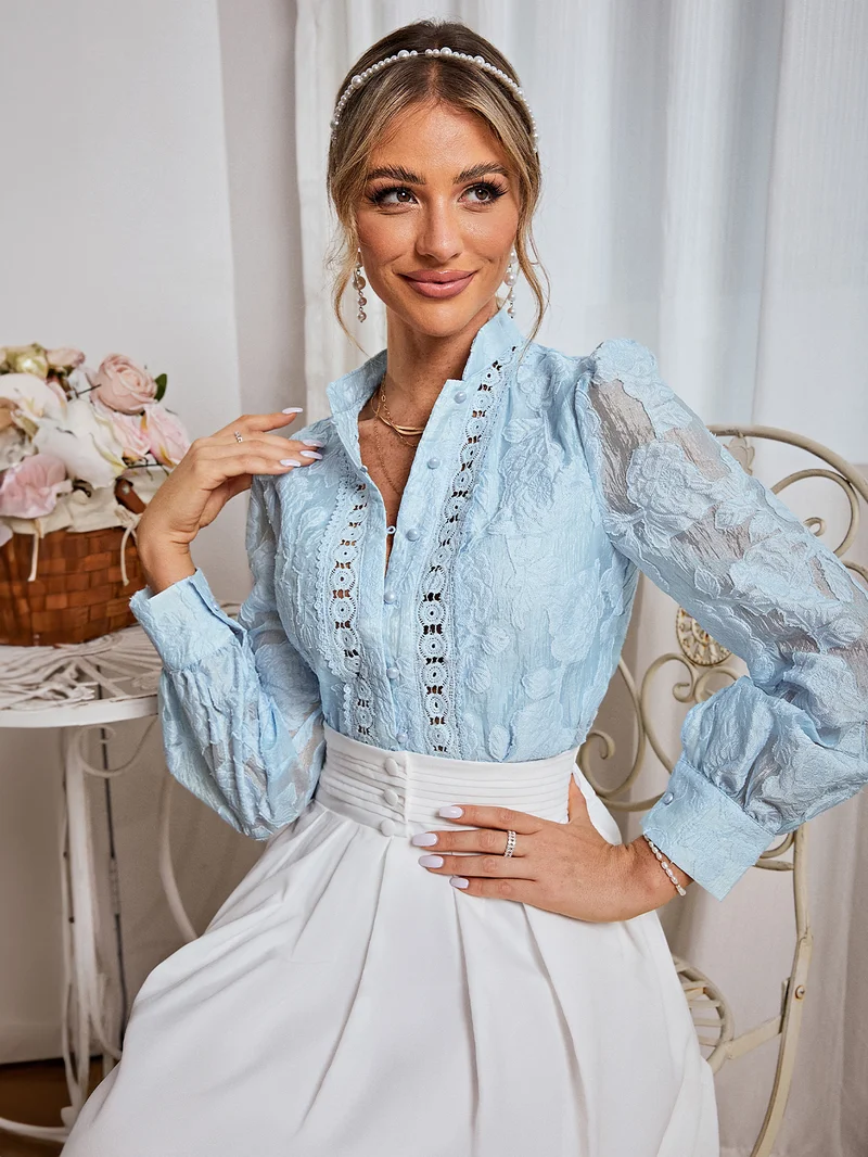سيمبلي بلوزة بياقة واقفة وأكمام بالون فضفاضة مزينة بالدانتيل الزهري المنفوش باللون الأزرق الفاتح والوردي الرومانسي.
