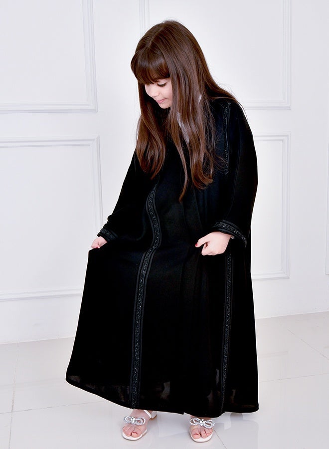 HAWRAA ABAYA Black girls’ abaya featuring long vertical embellishments, designed with a snap-button closure - Image 1