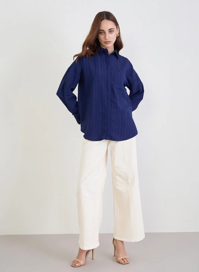 ستايلي بلوزة واسعة بتفاصيل بارزة الملمس مع أكمام مكبلة بأزرار