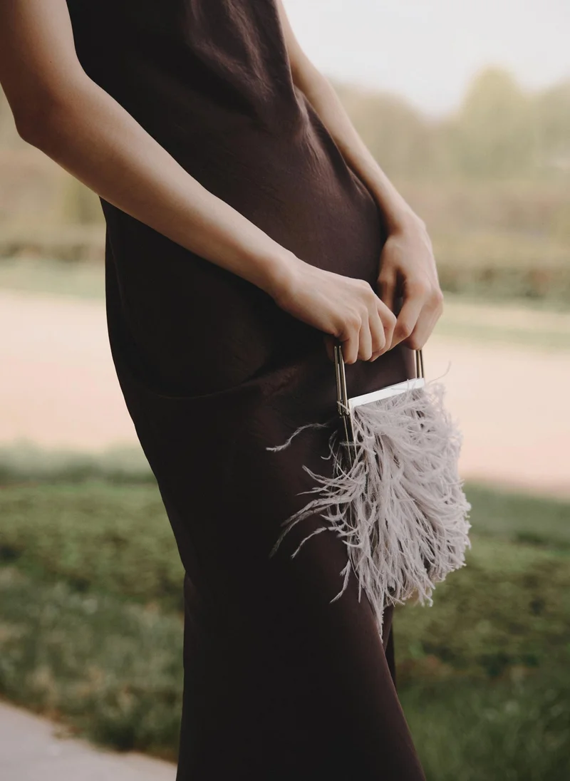 Clutch bag with feather detailing and a metal handle