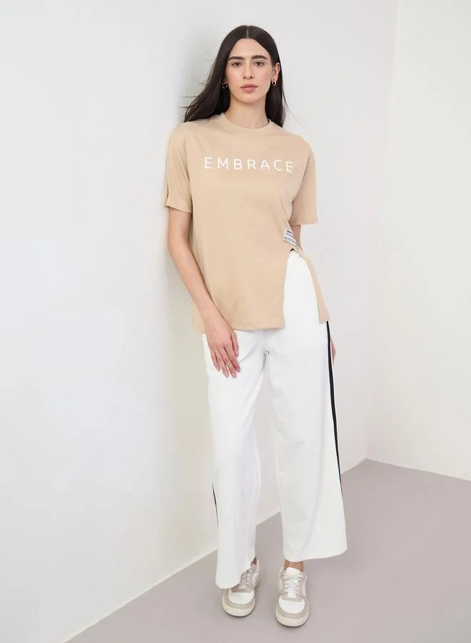 Styli Beige 100% Cotton Oversized T-Shirt with Slit and Badge Detail
