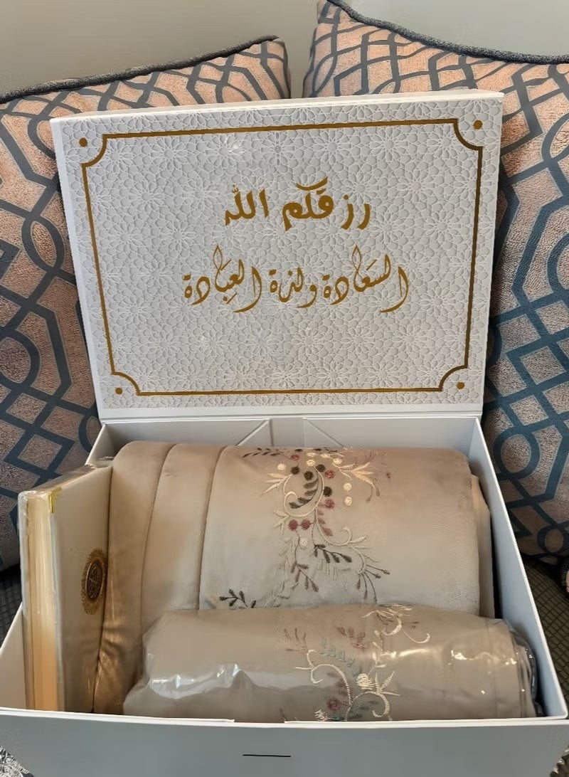 Elegant women's prayer set: prayer gown and mat, with a Quran and prayer beads.