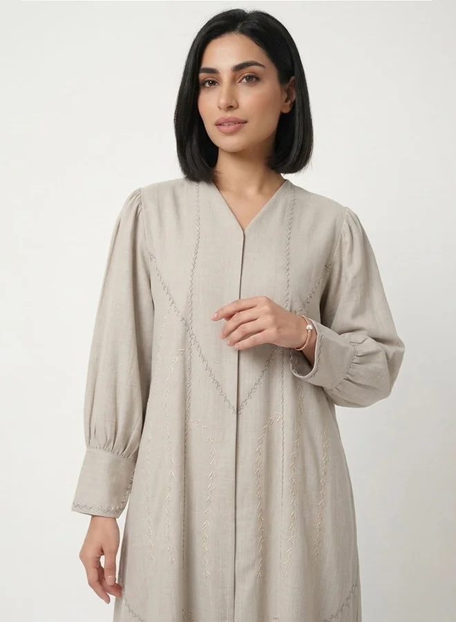 HAWRAA ABAYA Beige closed abaya with snap-button closure, adorned with delicate embroidery and subtle embellishments