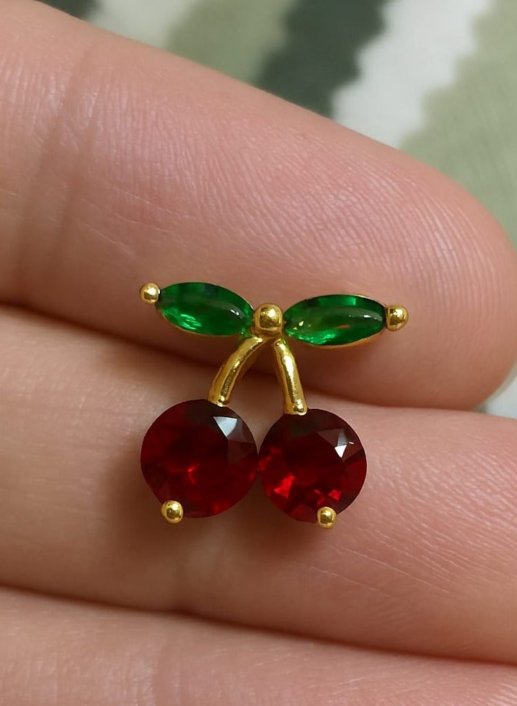 "A playful, feminine touch - made of stainless steel. Add a fresh, playful touch to your look with this cherry earring. Its unique design combines two rich red beads with an elegant gold stem, punctuated by tiny green leaves, adding a charming, natural touch. Perfect for those who love subtle details and unconventional, distinctive looks." - Image 3