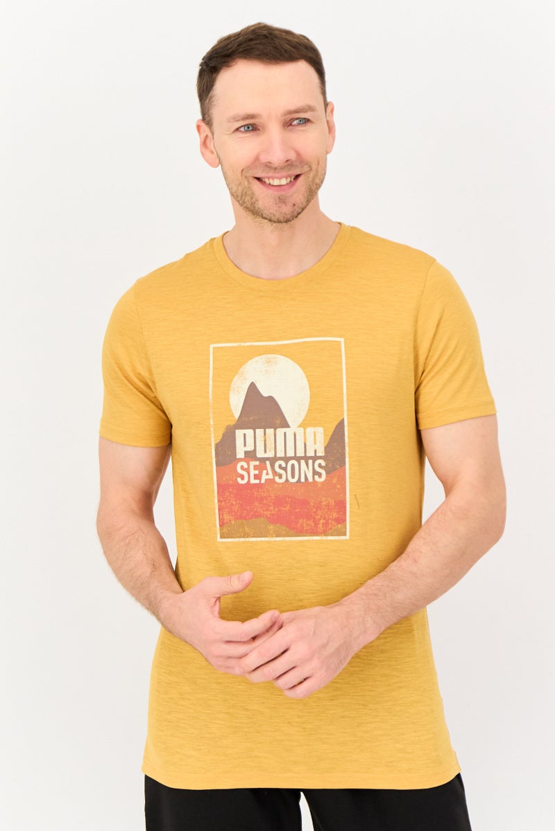 PUMA Men Sportswear Fit Short Sleeve Graphic Print Outdoor T-Shirt, Mustard - Image 1