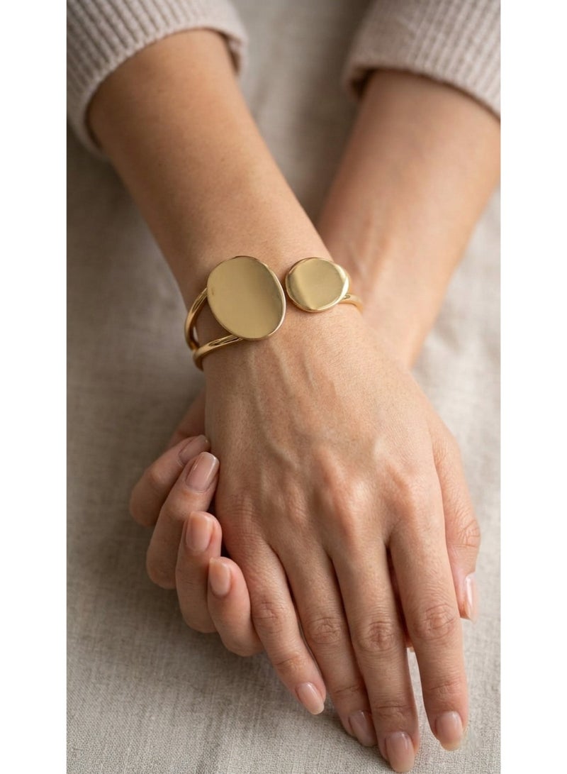 A sophisticated open gold cuff bracelet featuring a modern design with two asymmetrical circular ends and a smooth polished finish for a distinctive look