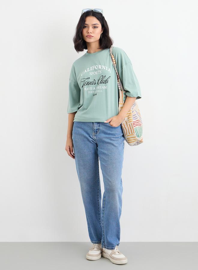 ستايلي تيشيرت نسائي واسع بطبعة شعار أخضر وكتف ساقط - Image 1