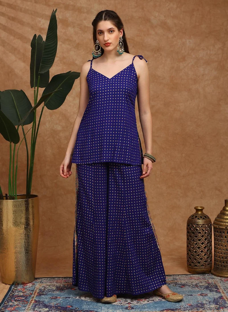 جلو باص طقم نسائي بلوزة وبنطلون بالازو باللون الأزرق بتفاصيل عرقية وطبعات ذهبية ورقبة على شكل  وحمالات ربط وشراريب