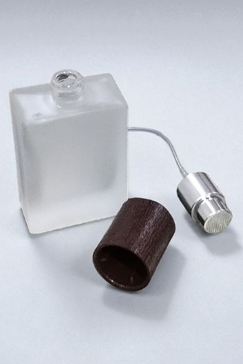 2 pieces of empty refillable spray perfume bottles so you can fill your favorite perfume and carry it with you at any time. The color of the glass is not transparent and frosty. The bottle cap is in the shape of a piece of wood. The color of the cap is brown and the other bottle is black. It is ideal in size and easy to carry and move. Put it in your pocket, bag, or even in a small evening bag for wives. It is a bottle designed for the bag. It does not take up space or room due to its suitable size. It is useful for travel, work, trips, wedding parties, or holidays. The bottle capacity is 30 ml. - Image 3