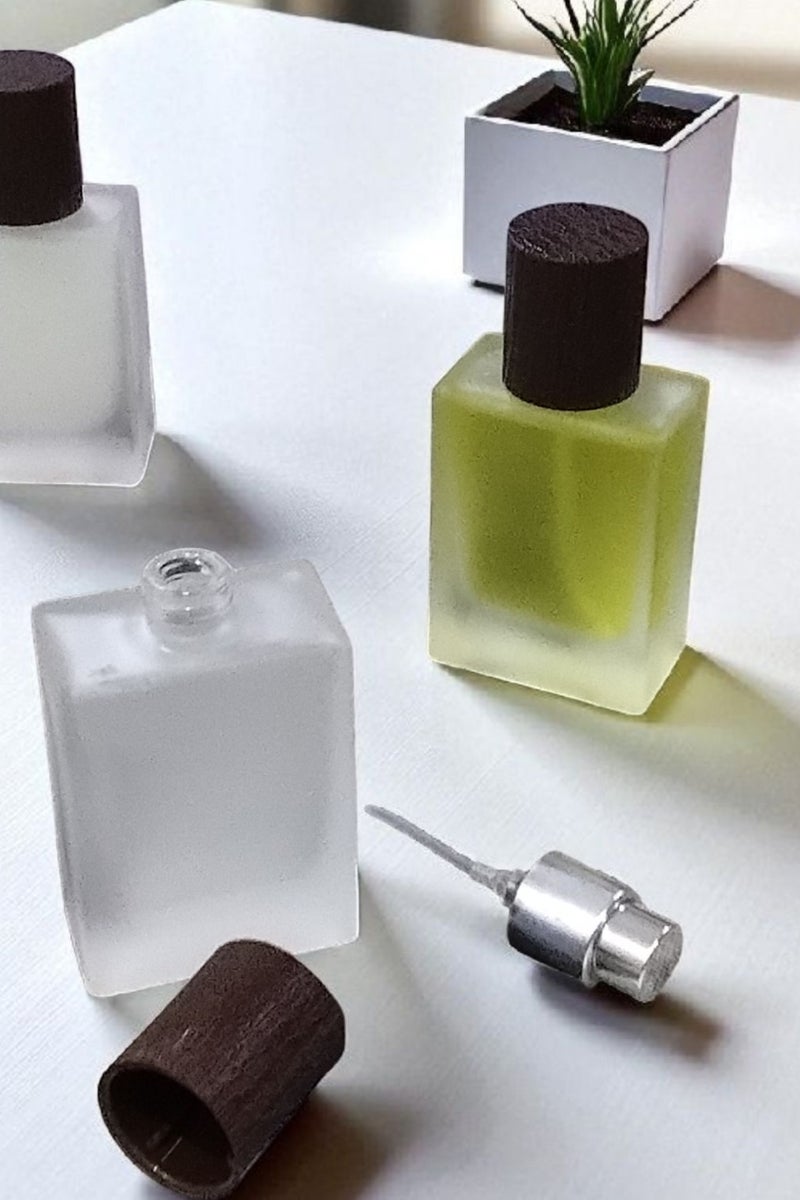 2 pieces of empty refillable spray perfume bottles so you can fill your favorite perfume and carry it with you at any time. The color of the glass is not transparent and frosty. The bottle cap is in the shape of a piece of wood. The color of the cap is brown and the other bottle is black. It is ideal in size and easy to carry and move. Put it in your pocket, bag, or even in a small evening bag for wives. It is a bottle designed for the bag. It does not take up space or room due to its suitable size. It is useful for travel, work, trips, wedding parties, or holidays. The bottle capacity is 30 ml. - Image 4