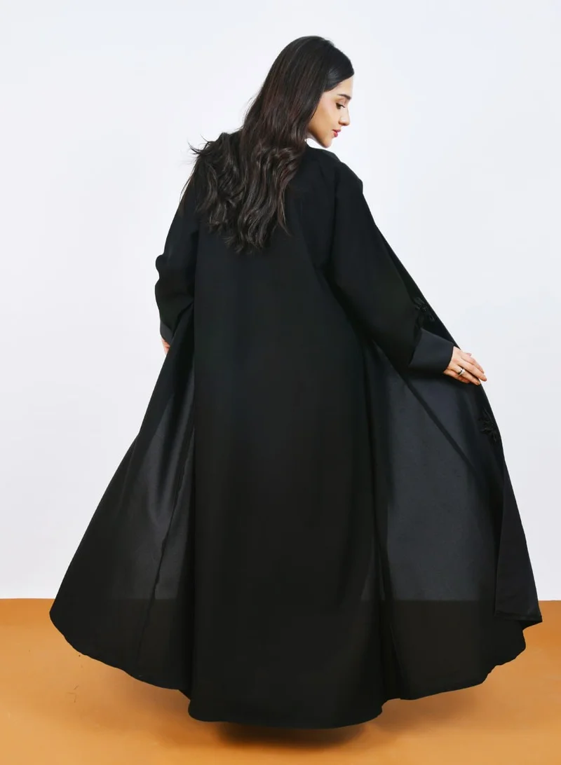 HAWRAA ABAYA Elegant black abaya with luxurious details, embellished with satin roses and hand-embroidered with a half-cloche cut.