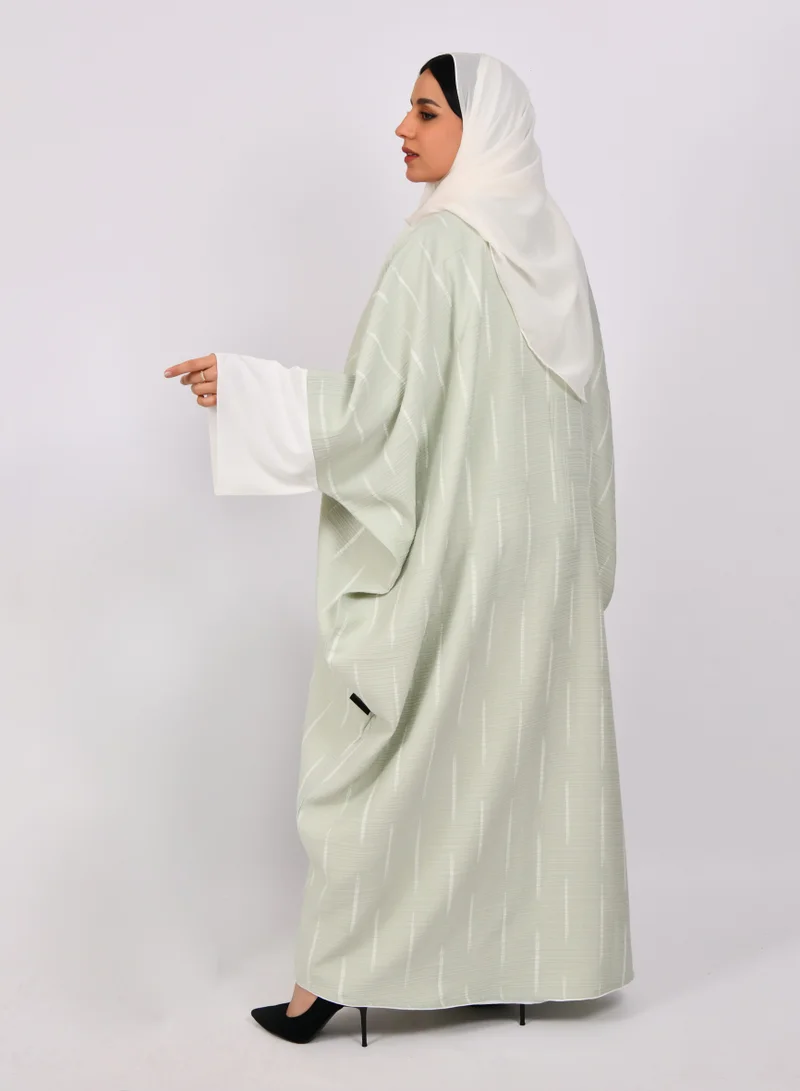 HAWRAA ABAYA Light green wide sleeve abaya with white stripes and a white dress