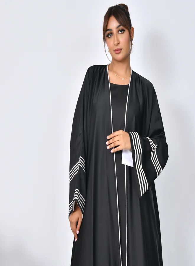 HAWRAA ABAYA Black abaya with wide sleeves decorated with white ribbons