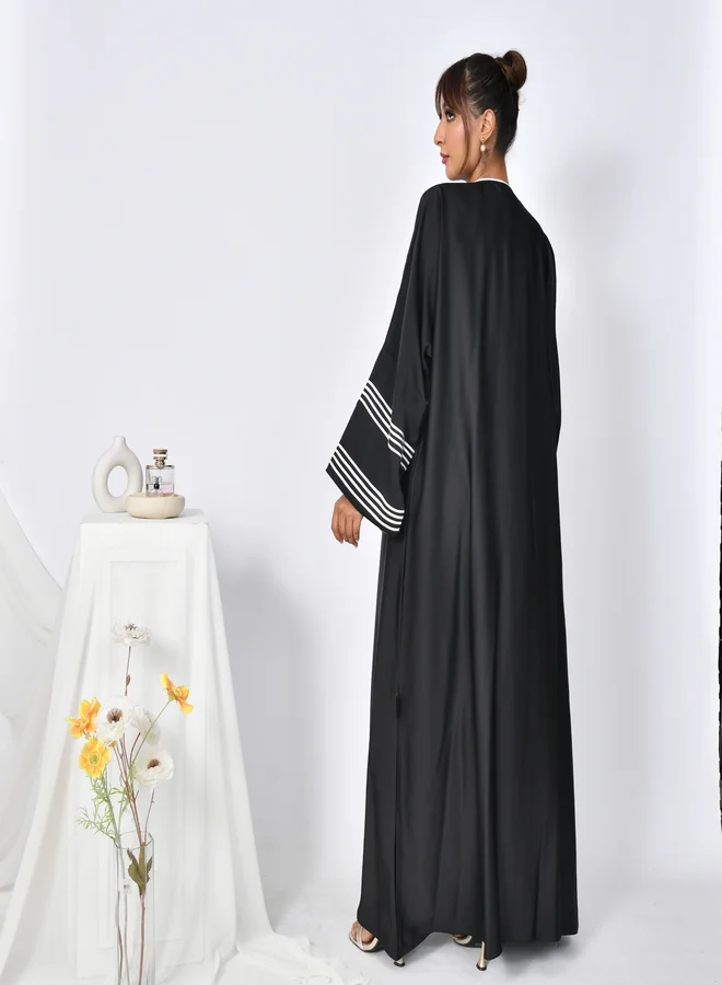 HAWRAA ABAYA Black abaya with wide sleeves decorated with white ribbons