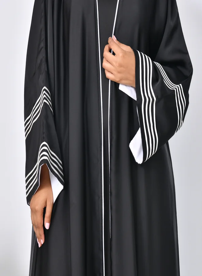 HAWRAA ABAYA Black abaya with wide sleeves decorated with white ribbons