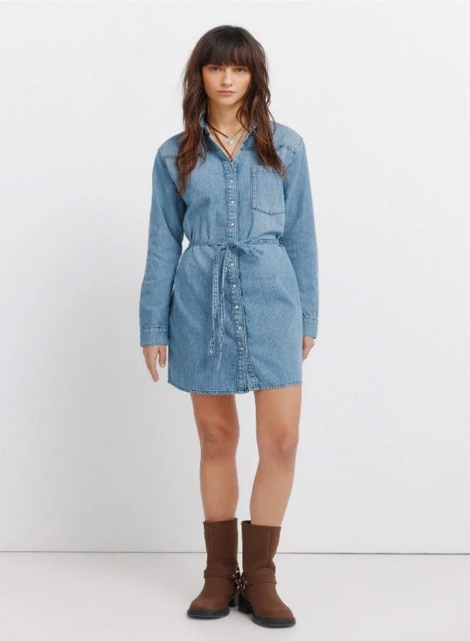 Denim short dress. Shirt collar. Front button and cuff fastening. Waist belt detail. V-shaped yoke. Studs on yoke. A washing process has been used with new technologies, reducing water, chemical and energy consumption.
