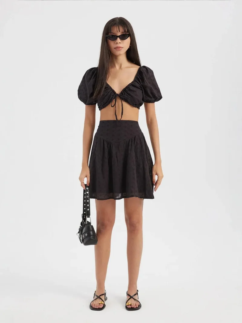 زوبعة قطعتان: بلوزة قصيرة بياقة قلب وربطة أمامية وأكمام منتفخة مع تنورة قصيرة مطرزة عالية الخصر ومرنة