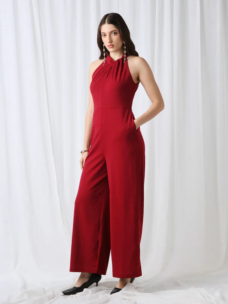 جلو باص جمبسوت نسائي مارون بياقة هالتر ملتفة بدون أكمام وتفاصيل ثنيات وأرجل واسعة للعمل