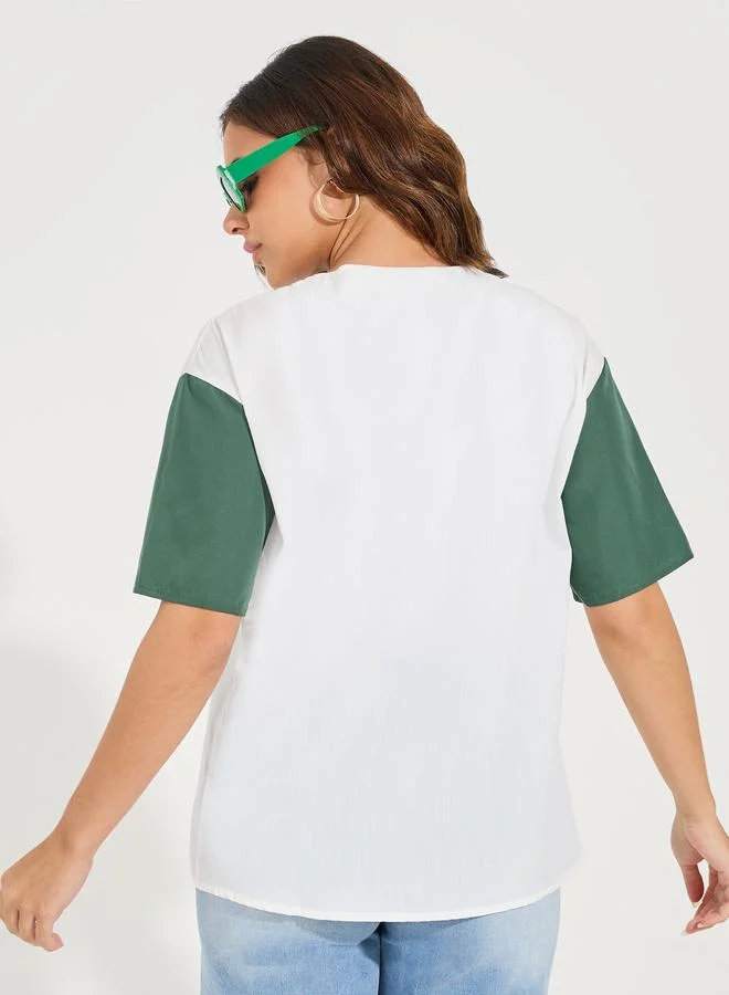 ستايلي بلوزة بلا ياقة مع طبعة فارسيتي واكمام بتفاصيل مُتباينة