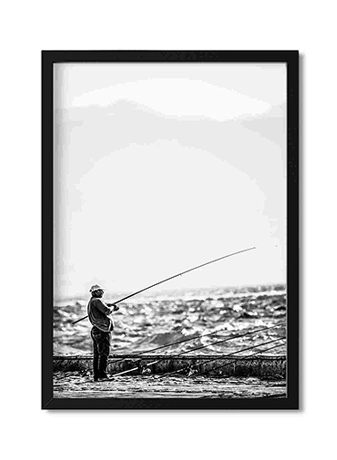 لوحة فنية لديكور الحائط برسمة رجل يقف بالقرب من شاطئ البحر حاملاً صنارة صيد متعدد الألوان 32x22x2سم - Image 1