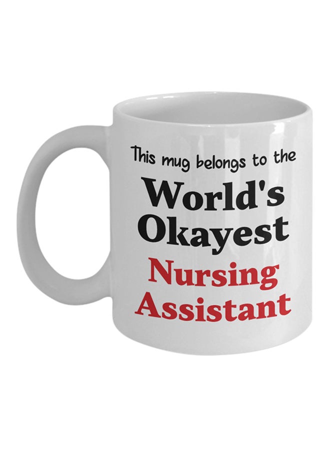 مج قهوة مطبوع عليه عبارة "World's Okayest Nursing Assistant" أبيض - v1572363651/N31216515A_1