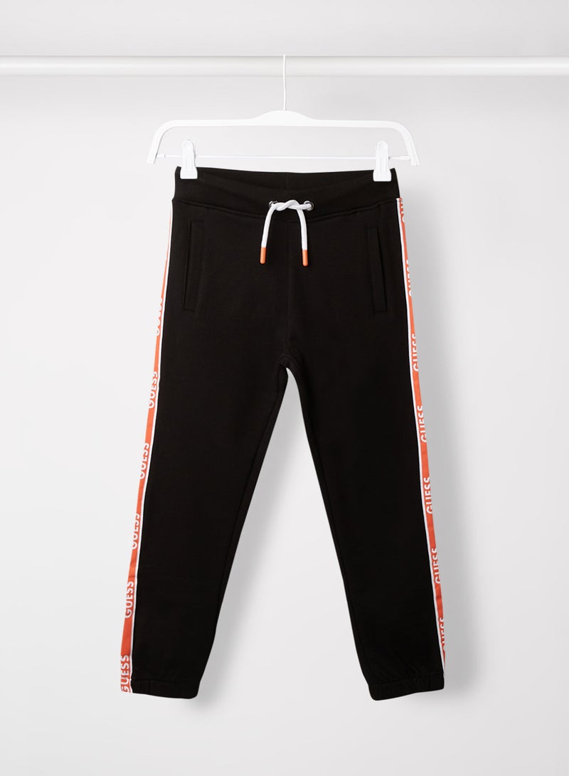 جس بنطال رياضي خفيف من قماش تيري بطبعة شعار على الجوانب للمراهقين/الصغار أسود حالك A996 - Image 1