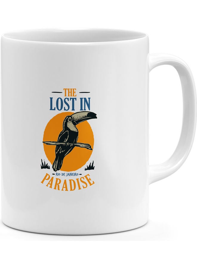 "مج قهوة مطبوع عليه عبارة "Lost In Paradise" مع صورة طائر متعدد الألوان - Image 1