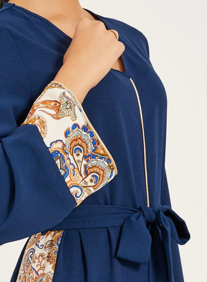 Styli navy olive colour jalabiya w/ navy blue pailsey print inserts at sides and slv cuff w/ gold cord trim at CF and sleeve hem