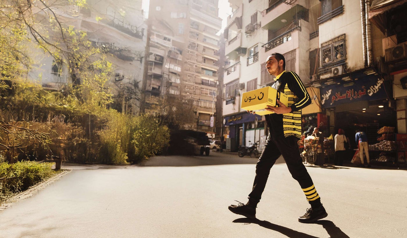 A noon delivery agent carrying a box for delivery in Dubai