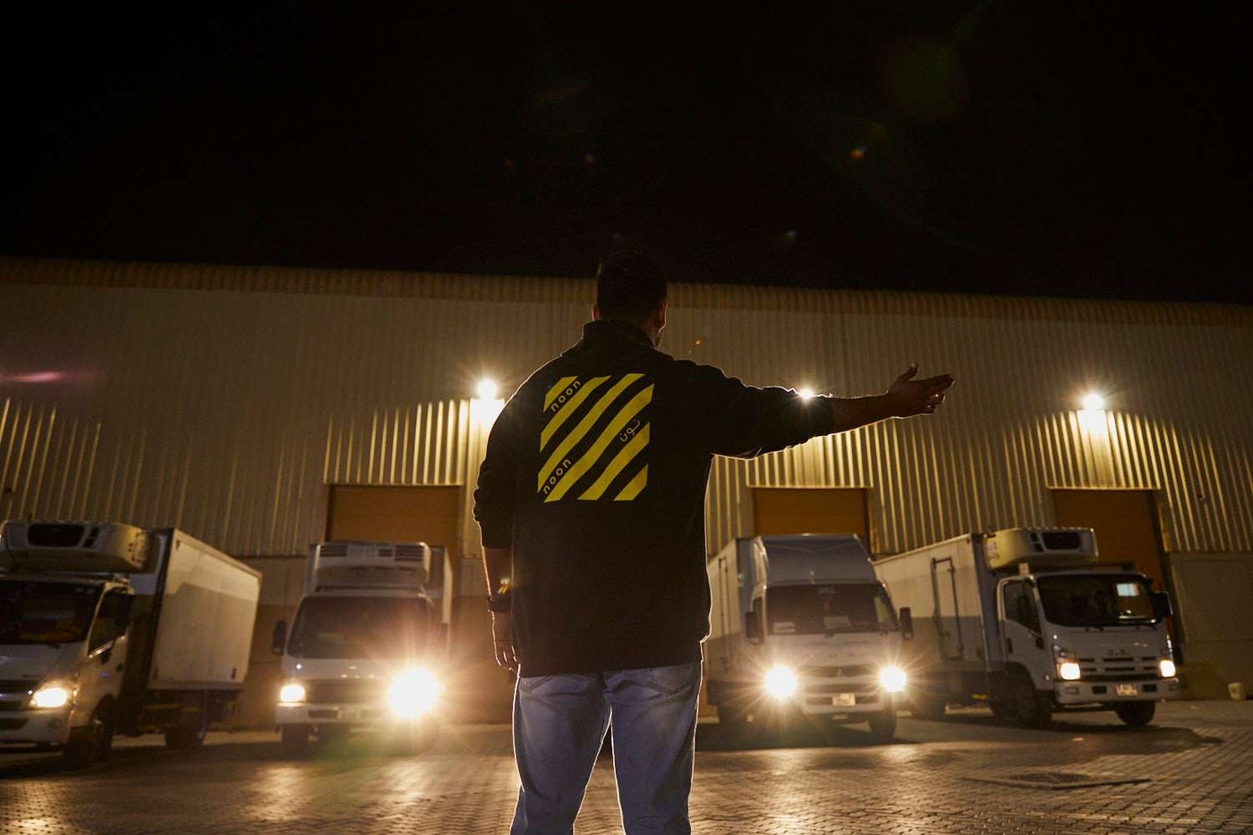 A noon employee instructing a fleet of delivery vans