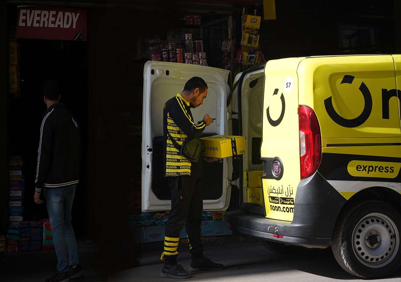 A noon delivery agent scanning a package by the back of his van